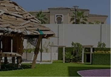 A grassy area with a hut and a house.