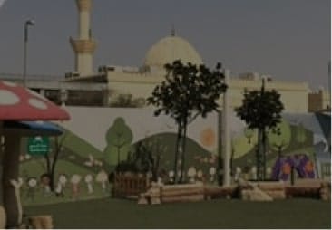 A children’s playground with a mural of a mosque in the background.