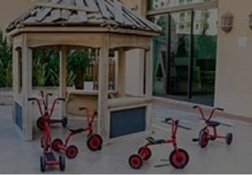 A group of red tricycles in front of a gazebo.