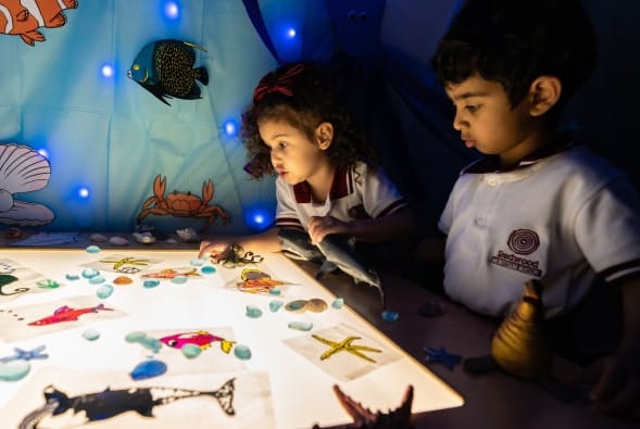 A group of children are playing with sea creatures on a table.